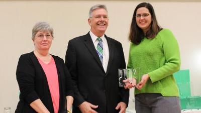 Two UNT staff members receiving a plaque from the provost
