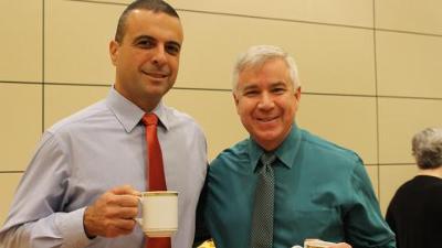 Two UNT staff members smiling with coffee in their hands
